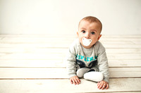 One year old cute baby boy sitting on wooden floor