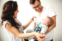 Hipster father, mother holding cute baby boy over white background