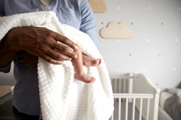 Close Up Of Father Holding Newborn Baby Son In Nursery