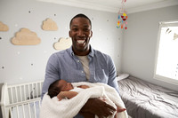 Portrait Of Father Holding Newborn Baby Son In Nursery